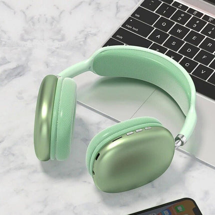 Green wireless over-ear headset resting on a keyboard, showing ear cup buttons