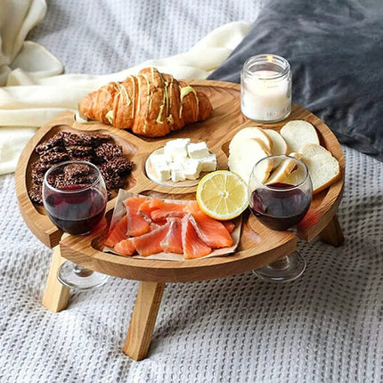 Wooden round folding picnic snack table with compartments, serving pastries and drinks