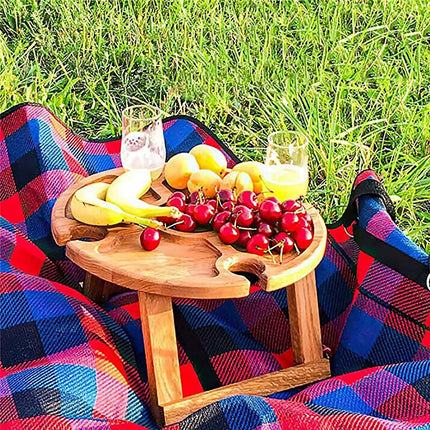 Wooden round folding picnic table holding fruit and appetizers on round tray