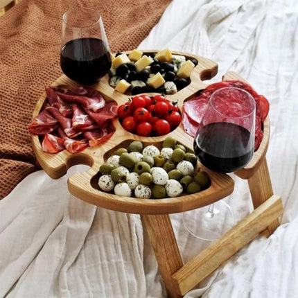 Wooden folding picnic table with round tray compartments, serving charcuterie and olives