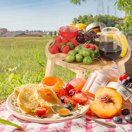 Wooden folding picnic table with round tray compartments, serving fruit and beverages