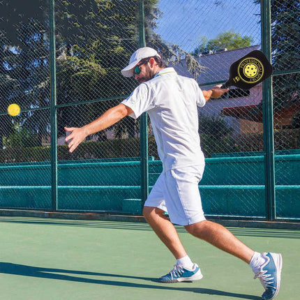 Pickleball paddle in use outdoors, black paddle face and grip visible