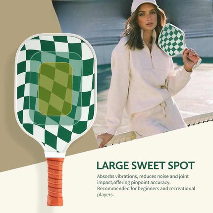 Pickleball paddle with green checkered face and orange grip, held by a woman